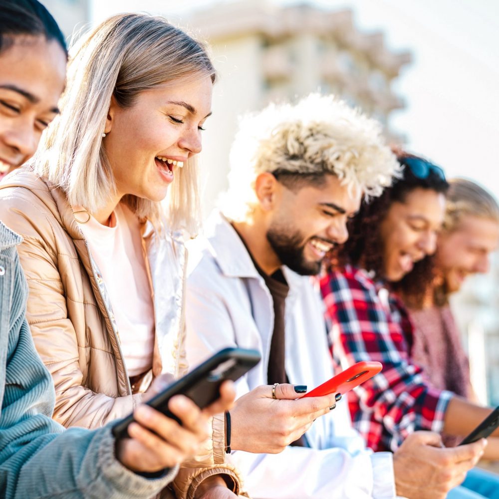 Trendy millenial friends using smartphone at campus college - Young genz people sharing live content with mobile smart phone - Tech life style concept with always connected millennials - Bright filter